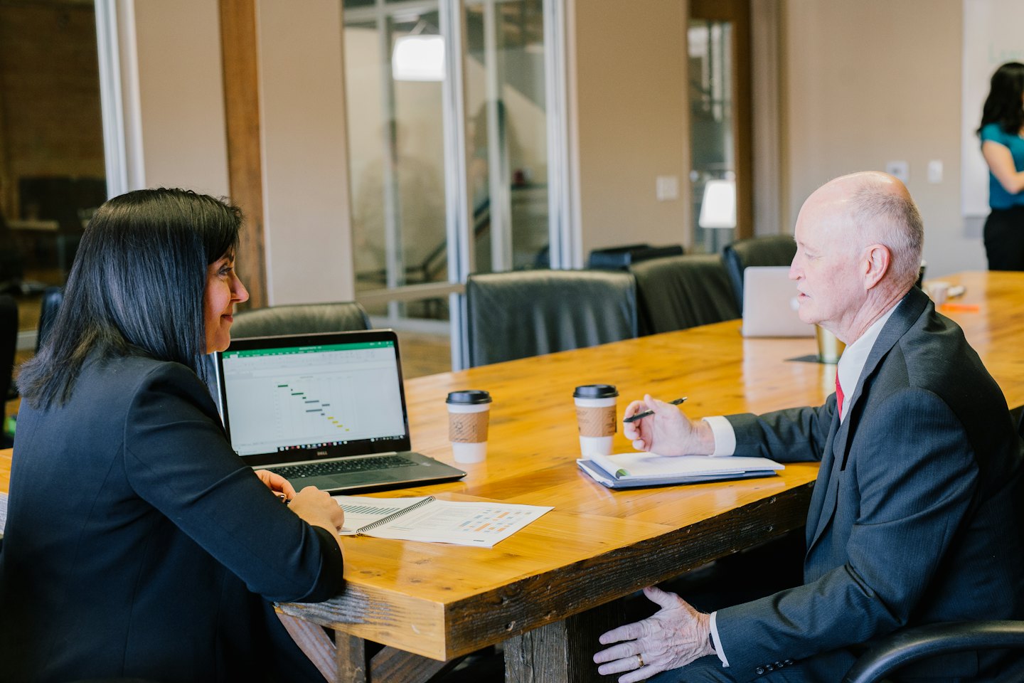 Profesionales de negocios discuten un gráfico en una laptop en una mesa de conferencias.